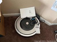 iRobot Roomba vacuum with charging station and manual on carpet