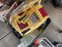 Top view showing colorful handmade quilts with patchwork and crochet trim inside a large plastic tub.