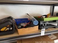 Photo showing assortment of power tools, accessories, and cases on metal shelf