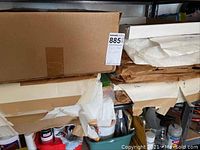 Shelf with large packages of tissue paper wrapped in paper and cardboard boxes.