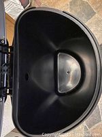 Close-up of large black plastic trash can with hinged lid showing interior