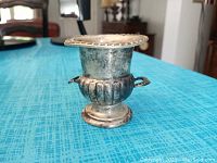 Side view of Wallace sterling silver miniature champagne bucket on blue surface.