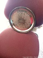 Top view of round sterling silver plated serving tray showing intricate engraved design and decorative rope rim.