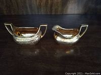 Cream and sugar set, front view showing gold-tone finish and floral pattern