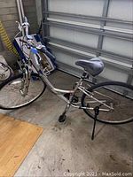 Full side view of the silver Shimano Cross Roads bicycle with kickstand down, showing general shape and condition