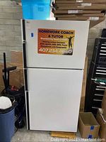 Front view of white Kenmore refrigerator featuring two doors and Homework Coach & Tutor sign attached to upper door.
