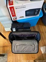 Open black structured travel and craft organizer bag with multiple compartments and dividers shown front view.