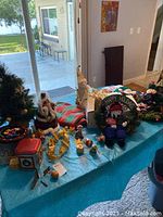Overview of the Christmas decorations on a table showing various vintage items including a green wreath with 'Happy Holidays', a snowman, tins, and figurines.