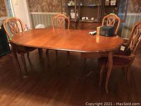 Close view of dining table, showing scalloped edge design and wood leg details