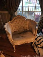 Front view of one chair showing tufted back, seat cushion and carved wooden frame.