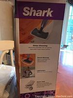 Box showing Shark branding and product benefits such as deep cleaning, swivel steering, lightweight design, and Shark pads with antibacterial protection.