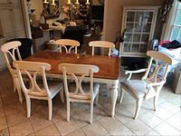 Photo showing the entire dining table with five chairs around it, white painted legs and backs with wood stained tabletop