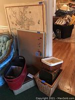 Photo showing the vintage world map leaning against the wall beside the cork board and several baskets and magazine holders arranged nearby.