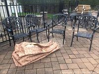 Four wrought iron chairs arranged on pool deck with cushion bag in front