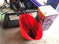 Photo showing four black metal tiki torches placed inside a large red plastic ice tote, with a box for the insect zapper next to it.