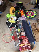 Wide view of all outdoor game equipment grouped together showing variety of items including net, balls, bags, and games.
