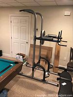 Full side view of the Weider pull up and dip exercise station near a pool table in a basement room.