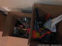 Overview photo showing cardboard boxes filled with assorted toys including knights and toy weapons