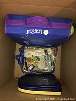 Top view of entire lot in box showing purple LeapPad tablet, Reading & Writing activity set in clear pouch, and Phonics Writing Desk
