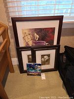 Four wall art pieces leaning against a wall, three framed and one unframed abstract canvas in vibrant blue and purple colors.