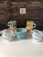 Photo showing 4 Fireking domino pattern bowls, 4 Termo Rey mugs with blue floral design, and 4 Fireking mugs in stacked pairs with different geometric and floral patterns.