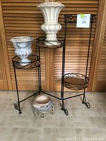 Full view of plant stand with three planters and urns arranged on and around it.