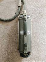 Full top-down view of the vintage grey Electrolux cylindrical vacuum cleaner with handle and attached hose.