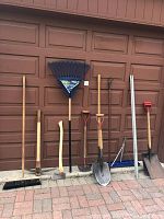 All tools lined against garage door, left to right: broom through snow shovel