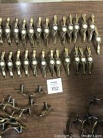Full lot overview showing 27 cabinet pulls arranged on a table including white medallion pulls, plain brass-tone pulls, and greenish medallion pulls.