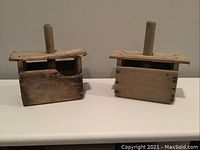 Front view of two wooden butter presses with distinct carved designs and vertical handles