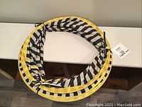 Collapsed view of the IKEA play tunnel showing circular yellow rim and black/white striped fabric in a folded state.