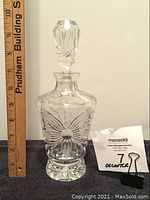 Front view of the crystal decanter with floral etching, stopper in place, with scale ruler to show size