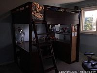 Full view of dark brown loft bed with ladder attached, shows top bunk, desk and shelving below