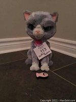 Front view of FurReal Friends Bootsie interactive cat toy with visible face and toy fish on the floor.