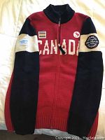 Front view of the red, black, and white women's wool sweater with Canada text and Paralympic patches