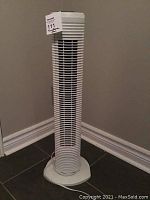 Full view of the tall white tower fan showing vertical grille and base.