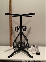 Single photo of the wrought iron table base legs showing the full height and decorative scrollwork design