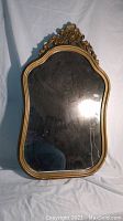 Full view of the antique mirror showing curved edges, gold frame, and overall condition.