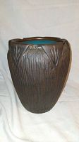 Full frontal photo of the vase showing dark brown textured exterior with vertical and leaf-like patterns and undulating rim shape.