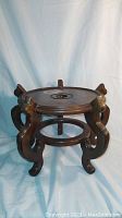 Photo of large Asian wooden plant stand showing circular top and curved legs