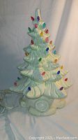 Front view of assembled ceramic Christmas tree lamp showing white glaze, green accents and multicolored plastic bulb inserts