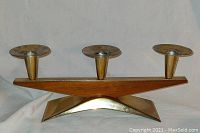 Front view showing three candle cups atop teak base and brass finish metal base.