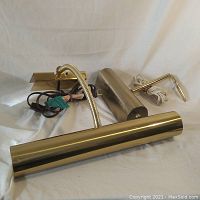 Pair of artwork lighting lamps showing metal and wood mounted tops with attached power cords.