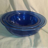 Side view of nested set of three Pyrex blue glass bowls showing sizes.