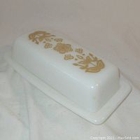 Closed view of the white milk glass butter dish with gold floral pattern on lid.