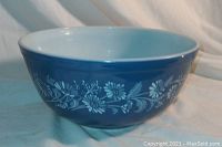 Side view showing blue exterior and white daisy floral pattern on Pyrex mixing bowl.