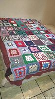 Full view of vintage crochet blanket spread over bed, showing color variation and size.