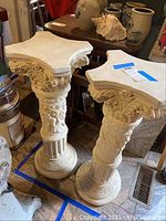 Pair of cream decorative pedestals with Corinthian capitals, front view