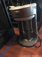 Full view of the Hamilton Beach professional milkshake machine showing its vertical metallic design and power cord.