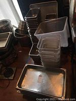 Photo showing stacks of stainless steel pans and plastic storage containers in various sizes and shapes